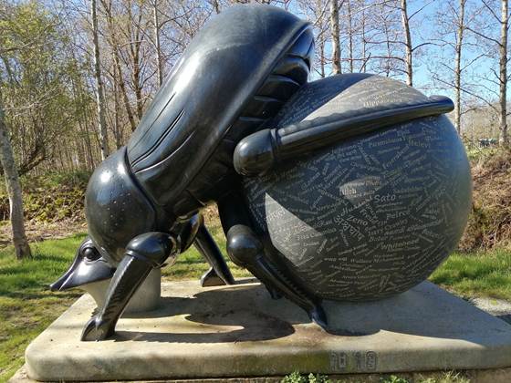 A statue of a bug carrying a large ball

Description automatically generated